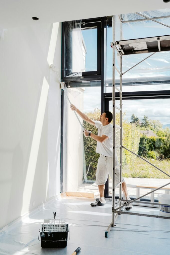 Man painting interior walls with roller in his house into white. Apartment renovation, redecoration